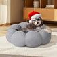 Dog wearing a Santa hat on a gray fluffy pet bed in a room with wooden furniture.