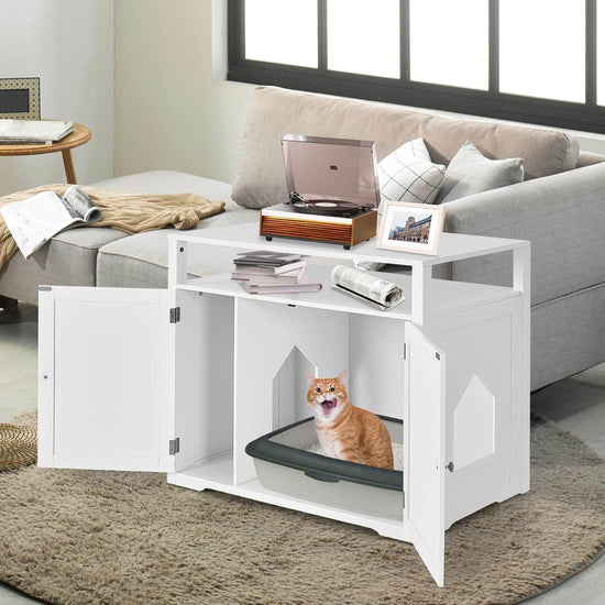 White pet litter box enclosure with a cat inside in a living room setting.