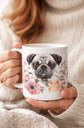 Person holding a mug with a pug design and floral elements